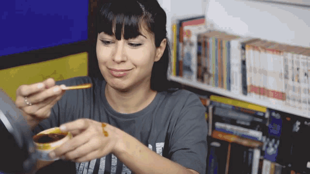 a woman wearing a gray shirt with the letter t on it is eating something