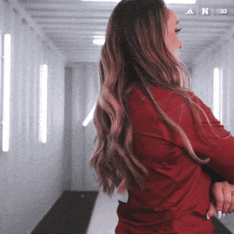 a woman in a red shirt is standing in a hallway with the letters a and n on the bottom