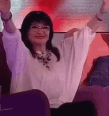 a woman is sitting in a stadium with her arms in the air and smiling .