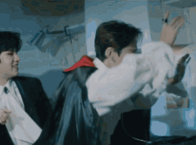 a couple of men are standing next to each other in a room . one of the men is wearing a cape .