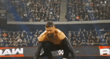a wrestler is jumping in the air while another wrestler is laying on the ground