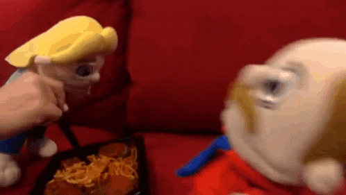 two stuffed animals are sitting on a red couch eating spaghetti and pizza .