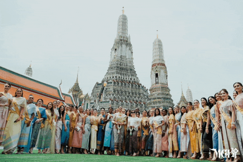 a group of women are posing in front of a temple and the word mcvs is on the bottom right