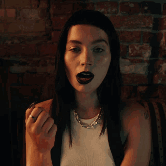 a woman with black lipstick on her lips and black nails