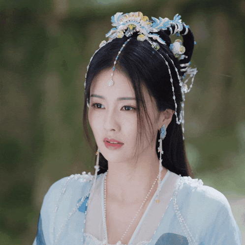 a woman wearing a blue dress and a headpiece with blue and yellow beads