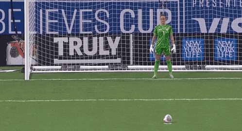 a soccer goalie stands in front of a believes cup truly sign