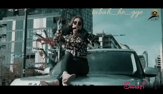 a woman is sitting on the hood of a car with the words tabah ho gye written above her