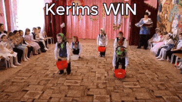 a group of children are performing in front of a crowd with the words kerims win written above them