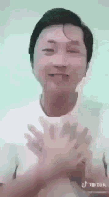 a man in a white shirt with his hands on his chest is smiling .