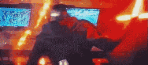 a blurry picture of a man standing in front of a computer monitor with flames coming out of it .