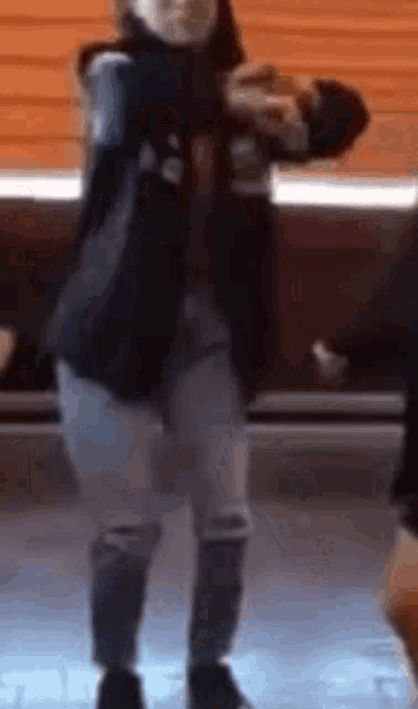 a person wearing a mask is dancing in front of a window