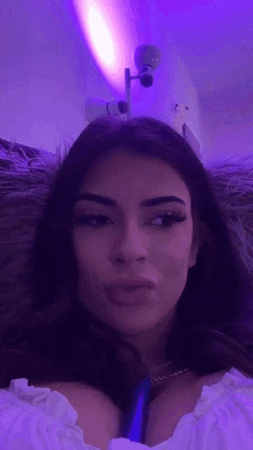 a woman is laying on a couch with purple lights behind her