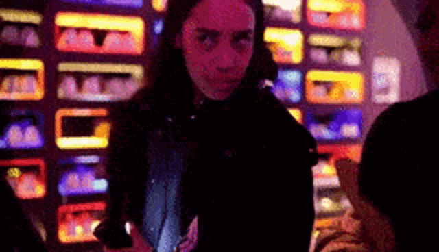 a woman is standing in front of a slot machine and looking at her phone