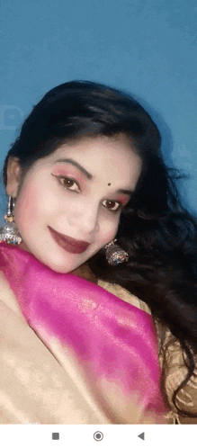 a woman wearing a pink scarf and earrings looks at the camera