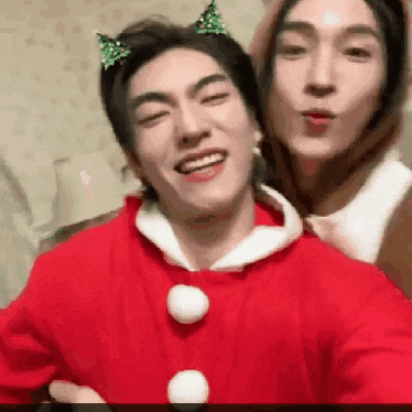 a couple of men are standing next to each other and one of them is wearing a santa claus costume .