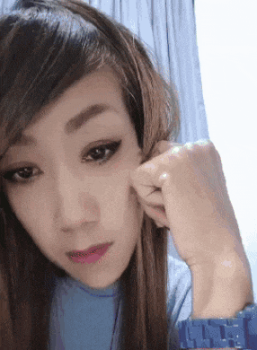 a woman wearing a blue shirt and a watch is pulling her hair