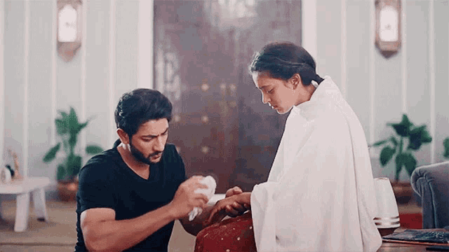 a man in a black shirt is putting a bandage on a woman 's arm