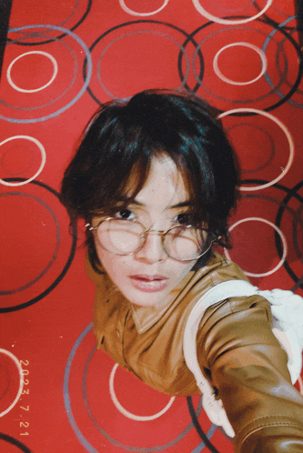 a woman wearing glasses is laying on a red rug with circles and the date of july 3 7 21