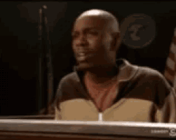 a bald man is sitting in front of a laptop computer and looking at it .