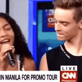 a man and a woman are standing next to each other in front of a cnn banner .