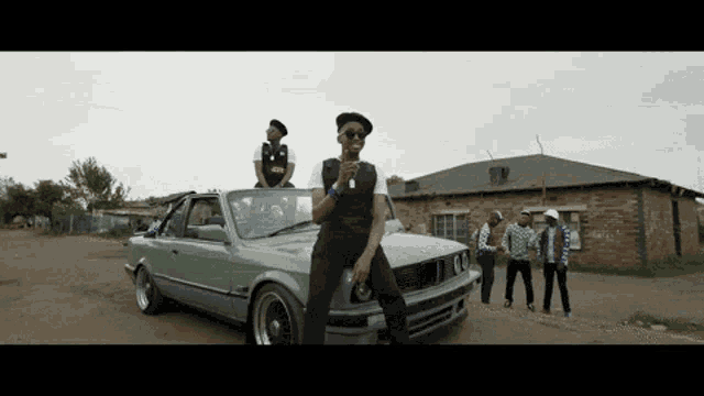 a man in a hat is standing next to a bmw car