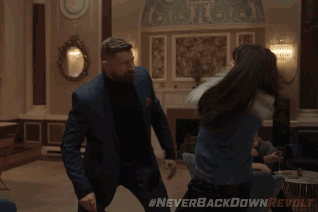 a man and a woman are fighting in a room with the hashtag neverbackdownrevolt