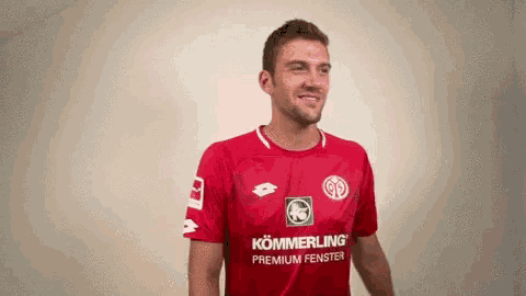 a man wearing a red shirt that says kommerling premium fenster on it