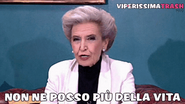 an older woman is sitting on a couch with the words non ne posso più della vita above her