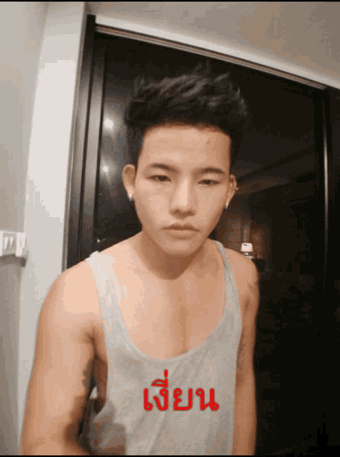 a man wearing a grey tank top with the word เขียน written on it