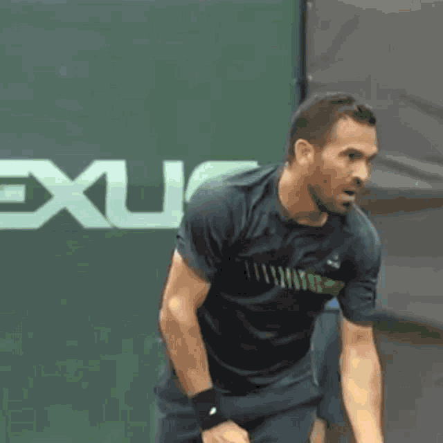 a man is holding a tennis racquet in front of a sign that says ' exit '