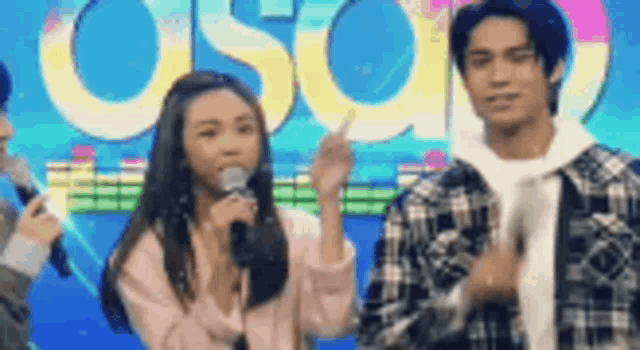 a man and a woman are standing next to each other on a stage holding microphones .