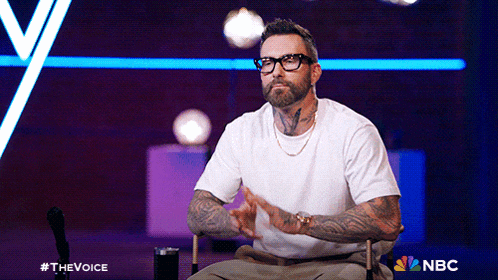 a man wearing glasses and a white shirt is sitting in a chair with nbc written on the bottom