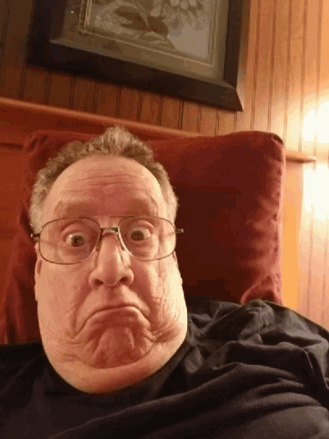 a man wearing glasses is making a funny face while laying on a bed