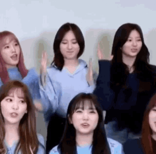 a group of young women are standing next to each other and raising their hands in the air .