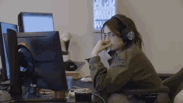 a woman wearing headphones is sitting in front of a computer