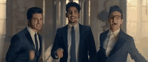 three men in suits and ties are standing next to each other and laughing .