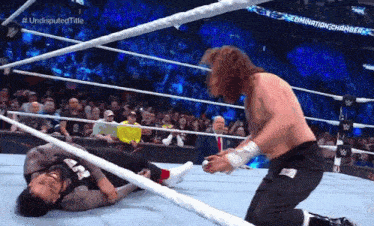 a wrestler is kneeling down next to another wrestler in a wrestling ring ..