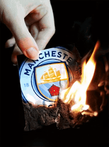 a person is holding a piece of paper with the manchester logo on it