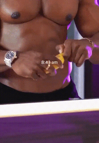 a shirtless man is peeling a banana and the time is 8:43