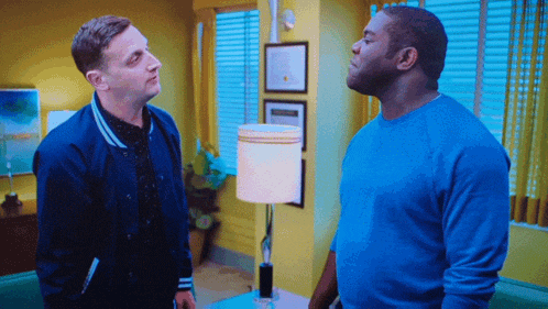 a man in a blue jacket talks to another man in a blue shirt