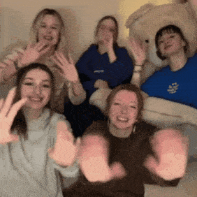 a group of young women are posing for a picture with a teddy bear .