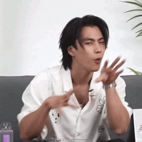 a young man in a white shirt is sitting on a couch making a funny face