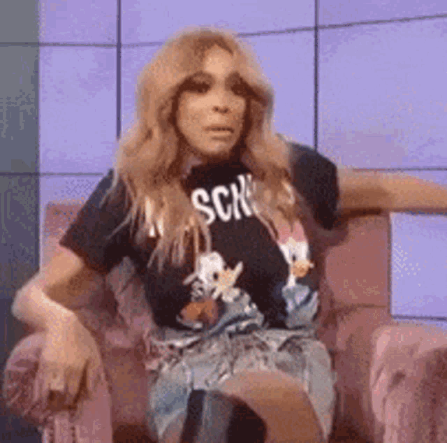 a woman is sitting in a chair wearing a t-shirt that says sch on it .