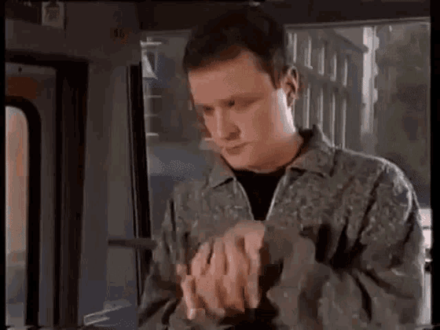 a man is sitting on a bus with his hands folded in front of him .
