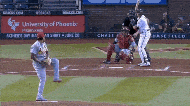 a baseball game is being played in front of a university of phoenix sign