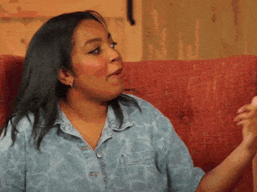 a woman in a denim shirt sits on a red chair