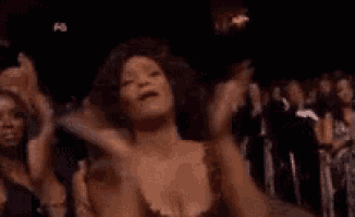 a woman is clapping her hands in a crowd of people at a concert .
