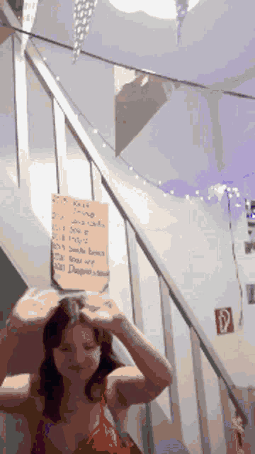a woman stands in front of a staircase with a sign on the wall that says 4.15