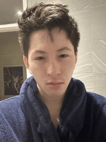 a young man with a blue towel around his neck looks at the camera