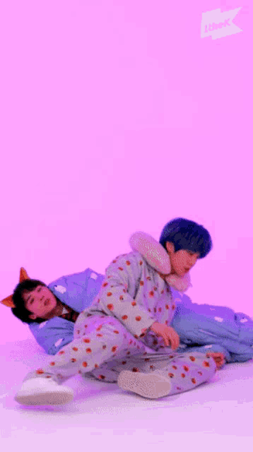 two boys in pajamas are laying on the floor with one wearing a neck pillow